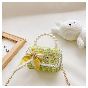 Detail of green tweed girl handbag with pearl handle, ribbon bow, and gold chain strap