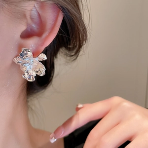 Close-up of silver irregular pleated flower earrings with liquid metal texture on model