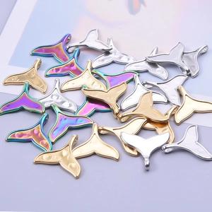 Detailed view of whale tail pendants in gold, silver and rainbow stainless steel
