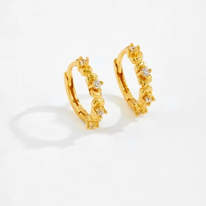 Detailed view of small gold huggie hoops with inset clear sparkling zircons