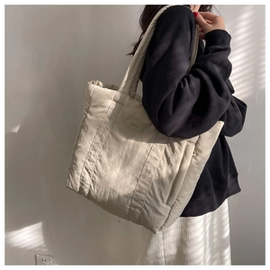 Detail of a large beige nylon tote bag showing quilted texture and side shoulder view
