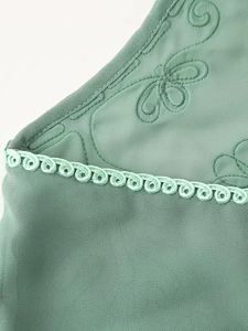 Vue macro détaillée du tissu vert menthe avec broderie florale et bord tressé