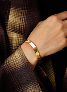 Close-up of minimalist irregular gold plated brass bangle on a female wrist