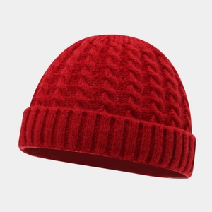 Detailed close-up of a red chunky cable-knit beanie with a wide folded cuff design