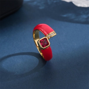 Elegant gold ring with red enamel and square red zircon gemstone on dark background