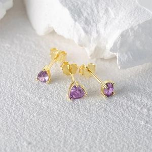 Macro detail of three gold-plated S925 silver studs with purple heart-shaped gemstones