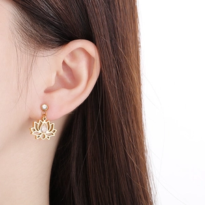 Gros plan détaillé d'une boucle d'oreille lotus évidée dorée avec zircon en forme de goutte
