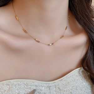 Detailed close-up of a minimalist gold beaded square adjustable choker necklace on a model