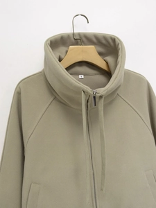 Detail of khaki zip-up hoodie featuring thick fleece texture and drawstring neckline
