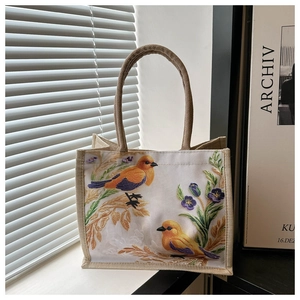 Detailaufnahme der Vogel- und Blumenstickerei auf einer strukturierten Leinentasche