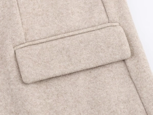 Close-up of a flap pocket on a soft beige wool blazer with detailed stitching