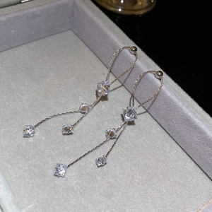 Détail de boucles d'oreilles pendantes argentées avec zircons carrés sur écrin velours