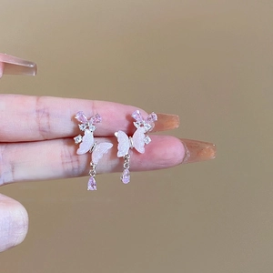 Vue rapprochée de boucles d'oreilles papillon roses avec gouttes en cristal violet
