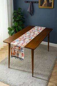 Detail of jacquard table runner with fish pattern and dark blue pom pom fringe trim