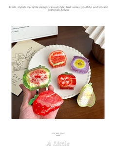 Detail of colorful acrylic fruit hair clips including strawberry and pear shapes on a tray