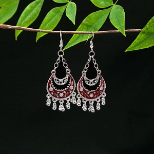 Macro detail of vintage tribal silver earrings with red hollow pendants and tassels