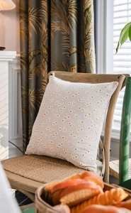 Linen daisy embroidered pillow on a vintage wooden chair in a rustic farmhouse setting