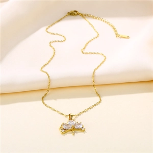 Elegant gold fan-shaped ginkgo leaf necklace with sparkling cubic zirconia on beige fabric
