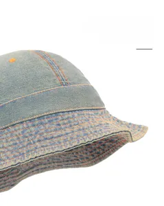 Détail rapproché d'un chapeau bob en denim bleu clair avec coutures orange décoratives
