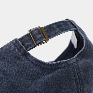 Détail de la boucle métallique et de la texture denim vintage à l'arrière de la casquette