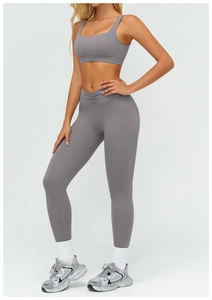 Dettaglio del set sportivo grigio con leggings a vita alta incrociata e reggiseno coordinato