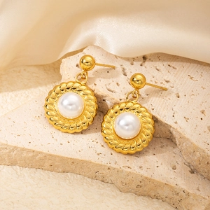 Macro shot of elegant vintage pearl earrings with gold twisted texture on beige stone texture