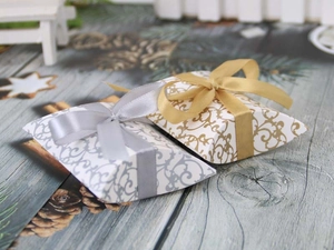Detail of silver and gold pillow gift boxes with baroque patterns and silk ribbons