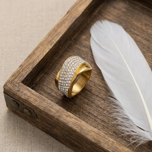 Detail of gold titanium ring with double rows of pavé diamonds on dark wood surface