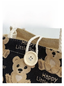 Close-up of jute lunch bag showing brown bear print, wooden button and woven handle