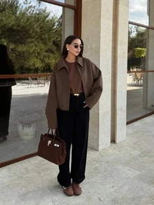 Outdoor shot of a vintage brown cropped zip-up jacket paired with black trousers and sunglasses