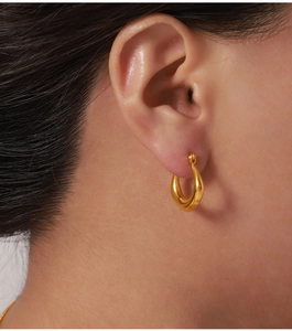 Détail macro de boucles d'oreilles en U plaquées or au design goutte minimaliste