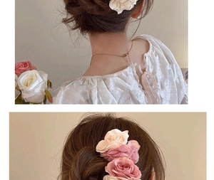 Vue détaillée d'épingles à cheveux en forme de roses en tissu rose et blanc sur un chignon