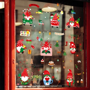 Christmas window gnome stickers with festive red car and tree decor on a glass window