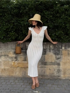 Détails d'une robe en crochet blanc montrant les motifs ajourés et le col en V sexy