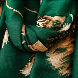 Detailed macro shot of soft dark green scarf with golden pine needle foil prints
