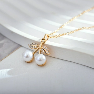 Macro shot of cherry pendant featuring white pearls and rhinestone-encrusted golden leaves