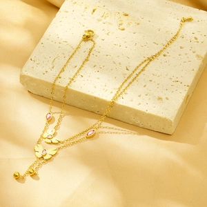 Detailed close-up of double-layer gold butterfly necklace with pink gemstones on silk