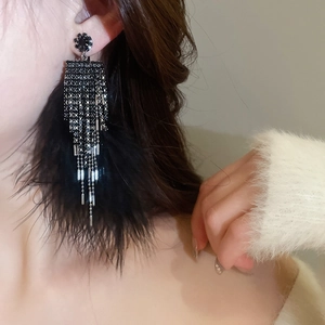 Macro detail of long black feather tassel earrings with sparkling rhinestones on model