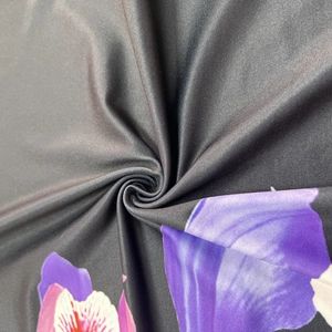 Détail de la maille extensible noire avec texture imprimée florale violette vive