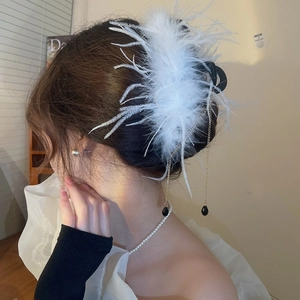 Detail of white feather hair claw clip with golden chains and black teardrop pendants