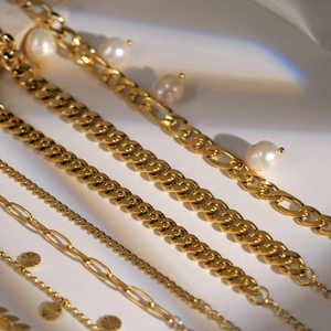 Macro shot of gold chains with white pearls showing diverse links and rainbow light effects