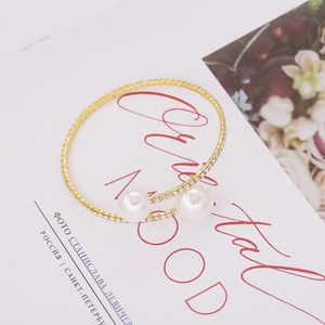 Detail of elegant gold open bangle with sparkling rhinestones and two large pearls