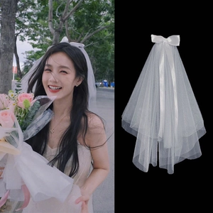 Short double-layer white wedding veil featuring a chic satin bow and pearl accents