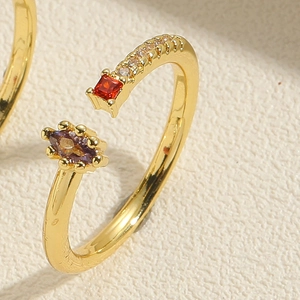 Detail of adjustable gold ring featuring red square stone and purple marquise zircon