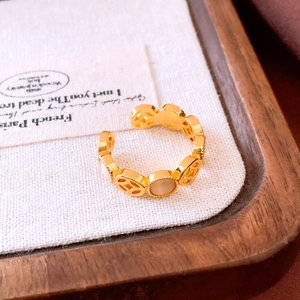 Detail of gold Chinese coin hollow ring featuring opal stone on a white linen display