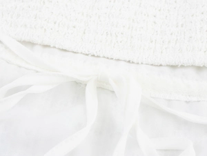Detail of white mesh dress showing fabric texture with tie-knot and drawstring design