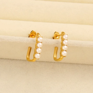 Macro shot of gold J-shaped hoop earrings with four vertical white pearls and butterfly back