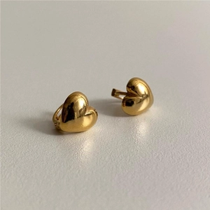 Detailed close-up of polished golden heart-shaped clicker earrings on a neutral background