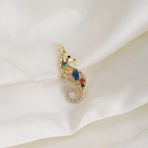 Detailed close-up of a golden seahorse pendant with colorful stones on white silk