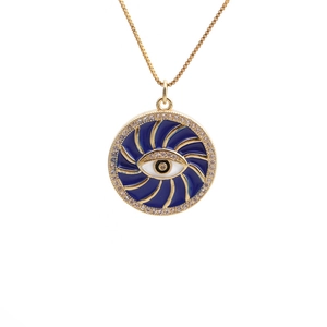 Evil eye pendant necklace with blue enamel and gold swirl pattern on white background